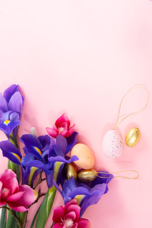 Easter scene with colored eggs and fresh flowers over pink backgroundの写真素材