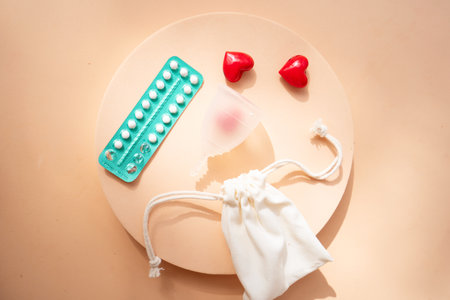 Menstrual cup and pack of contraceptive pills over beige background, eco friendly and zero waste solutionの写真素材