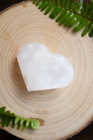 heart made of stone crystal with flower of life pattern on wooden backgroundの写真素材