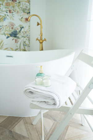 White bathroom with white fresh towels on chair