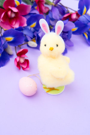 Easter scene with chiken in funny rabbits ears, flowers in backgroundの写真素材