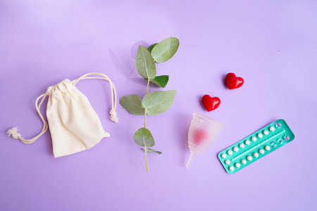 Menstrual cup and pack of contraceptive pills over violet background, eco friendly and zero waste solutionの写真素材