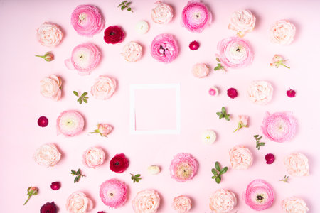 Flowers composition. Frame made of fresh roses and ranunculus flowers with leaves on pink background. Flat lay, top viewの写真素材