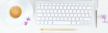 Flat lay top view home office workspace - modern keyboard with lilac flowers on white backgroundの写真素材