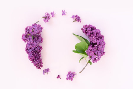 Fresh lilac flowers over pink background with copy space on heart paper note, flat lay floral compositionの写真素材