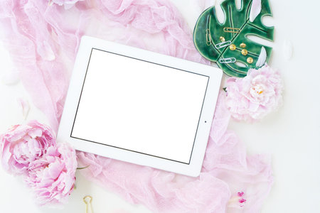 Creative wedding composition with tablet frame mock up, pink blanket, flowers on white background. Flat lay, top view stylish art concept.の写真素材