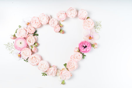 Floral composition. Heart frame made of pink rose and ranunculus flowers on white background. Flat lay, top view, copy spaceの写真素材