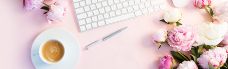 Flat lay home office workspace - modern white keyboard with cup of coffee and peony flowers, copy space on pink backgroundの写真素材