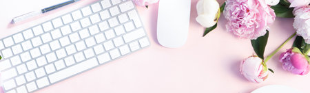 Flat lay home office workspace - modern keyboard with female accessories and fresh peony flowers, copy space on pink backgroundの写真素材
