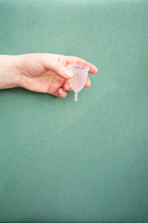 Hands holding menstrual cup over violet background, eco friendly and zero waste solutionの写真素材