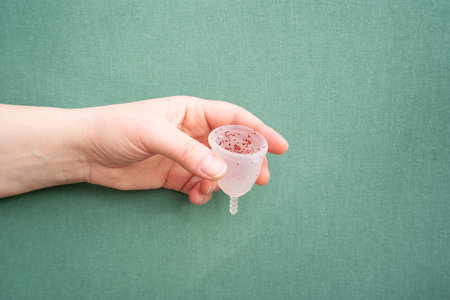 Hands holding menstrual cup over violet background, eco friendly and zero waste solutionの写真素材
