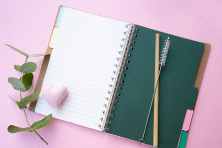 Zero waste concept with open notebook and green eucaliptus leaves over pink backgroundの写真素材