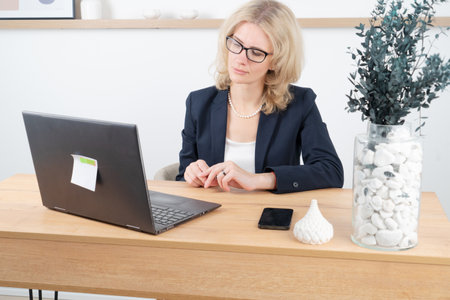 Happy 40s woman working with modern laptop at her home, distant work conceptの写真素材