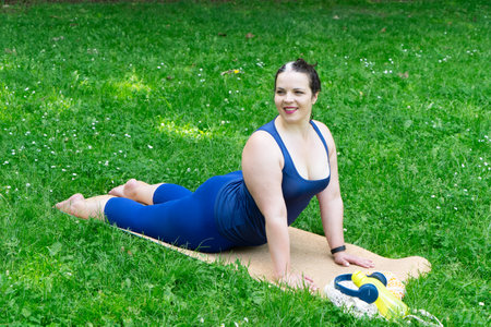 Woman and sports, exercise for stretching and weight loss in the fresh air. Happy curvy 40s woman doing workout stretch routine outdoor at city parkの写真素材