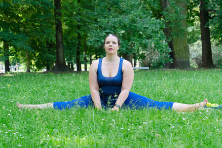 Woman and sports, exercise for stretching and weight loss in the fresh air. Happy curvy 40s woman doing workout stretch routine outdoor at city parkの写真素材