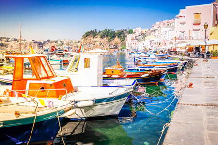 Procida island colorful town with moored boats at embankment, Italy