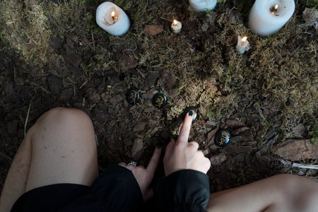 A captivating mystical scene depicts a woman deeply engaged in a nature ritual that includes candles and crystalsの写真素材