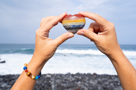 woman meditating on wild beach shore and holding crystal heartの写真素材