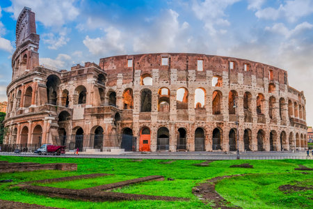 ruins of antique Colosseum with green grass lawn in sunise lights, Rome Italyの写真素材