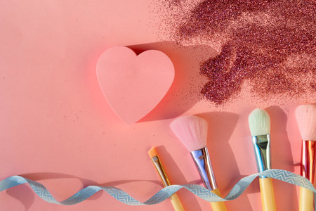 Minimal modern cosmetic scene with set of make up brushes set over pink background with glitter and shadow overlayの写真素材