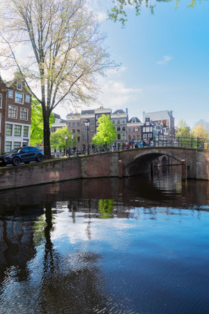 Facades of old historic Houses, bridges and trees over canal water, Amsterdam, Netherlandsの写真素材