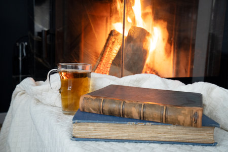 Imagine a cozy scene with beloved books, soothing tea, and a crackling fireplace for ultimate relaxationの写真素材