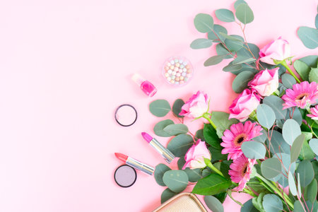 pink flatlay with flowers and cosmetics, soft feminine mood, rose bouquet and eucalyptus sprigs arranged beside lipstick, compact, beaded jewelry and pastelの写真素材