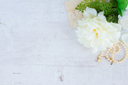 White fresh peony flowers with pearls jewellery on white wooden table with copy spaceの写真素材