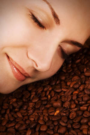 Beautiful girl's face over coffee beansの写真素材