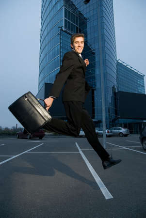 Happy business man running home after workの写真素材