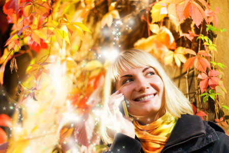 Happy girl talks to on the phone, abstract autumn background behind her