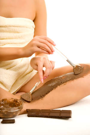 Beautiful woman applying chocolate mask to her skinの写真素材