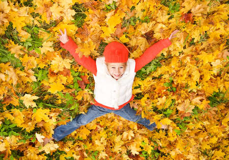 Cute little girl lying in autumn leaves