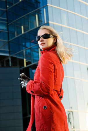 Beautiful young blond woman outdoors. Modern building behind herの写真素材