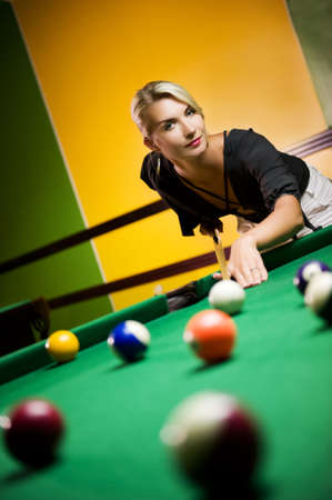 Beautiful blond woman playing billiards