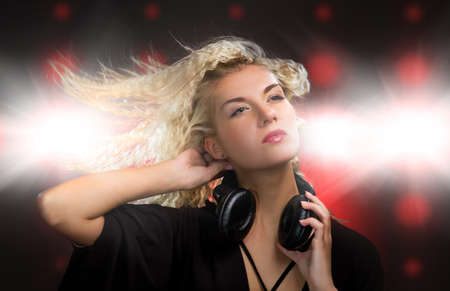 Beautiful young woman with headphones in nightclubの写真素材
