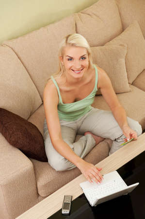 Happy young woman using credit card to make online purchase

の写真素材