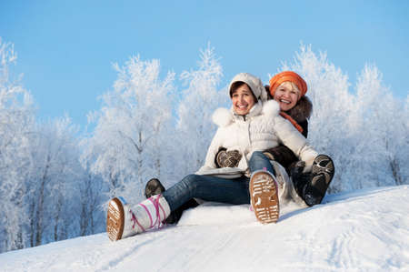Mother and daughter sliding in the snowの写真素材