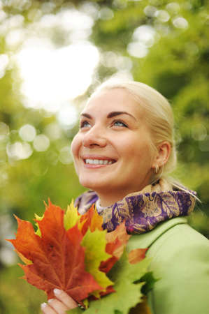 Woman with golden autumn leaves の写真素材