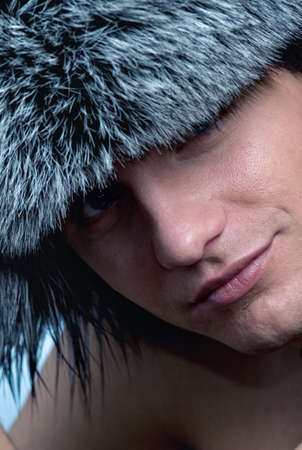 Close-up portrait of handsome young man wearing fluffy hatの写真素材