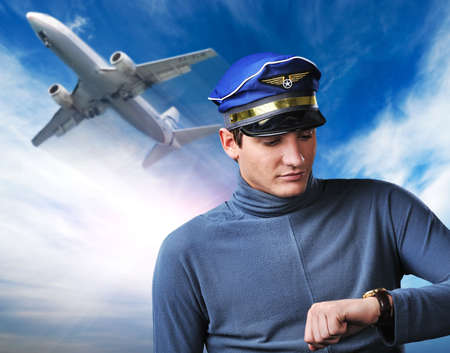Handsome pilot against blue sky and flying planeの写真素材