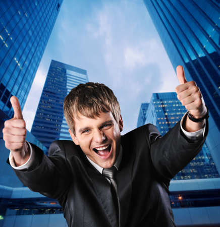 Happy businessman against his office buildingの写真素材