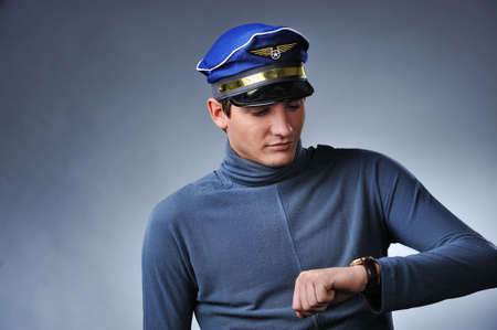 Handsome pilot looking to his watch. Isolated on grey backgroundの写真素材