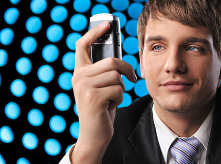 Young businessman holding mobile phone over abstract backgroundの写真素材