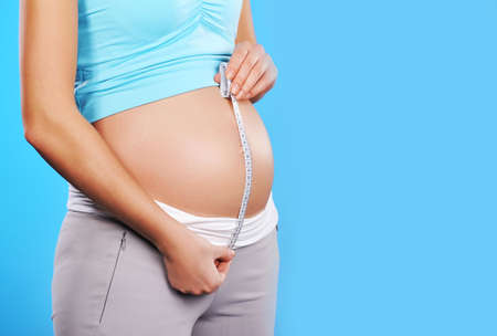 Pregnant woman measures her belly 
の写真素材