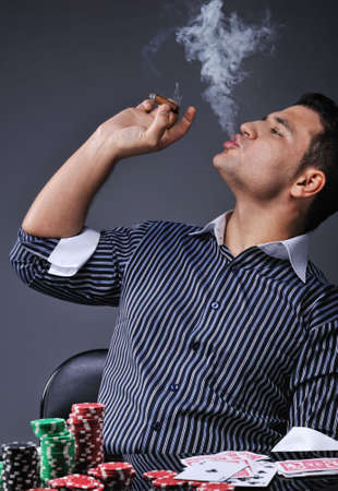Portrait of a young gangster smoking and playing pokerの写真素材
