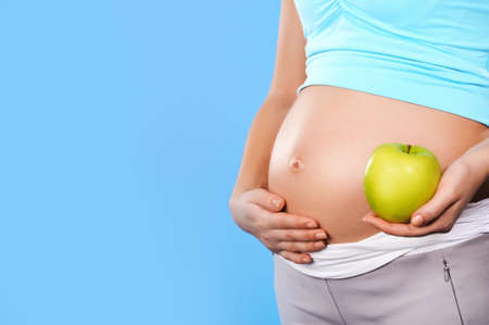 Beautiful pregnant woman with an appleの写真素材
