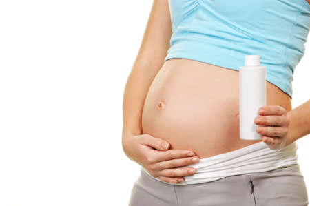 Beautiful pregnant woman holding a bottle of creamの写真素材