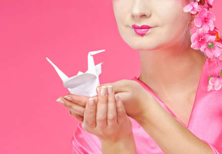 Beautiful geisha holding origami bird. Close-up portraitの写真素材