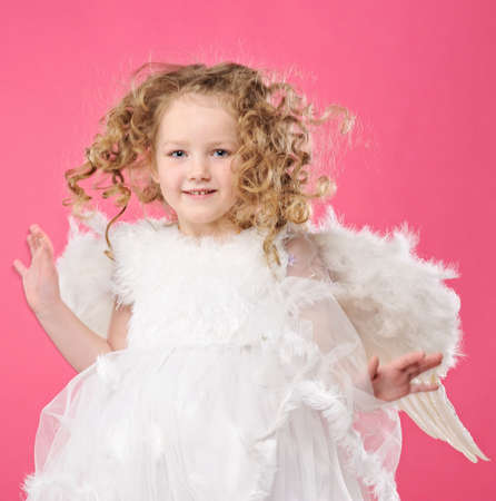 Beautiful little angel girl isolated on pink backgroundの写真素材